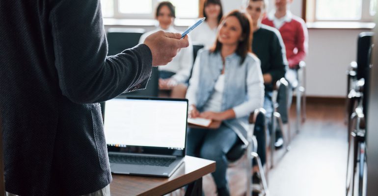 Everyone is smiling and listens. Group of people at business conference in modern classroom at daytime